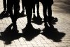 Silhouettes and shadows of people on the city street. Crowd walking down on sidewalk, concept of strangers, crime, society, gang or population
