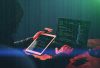A person is using multiple devices, including a tablet and a laptop, surrounded by digital code, highlighting themes of cybersecurity, technology, and potential criminal activities in modern policing.