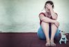 Upset women, victim of crime, sits against a wall with her hand over her face, and her dog alongside her